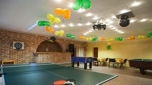 Une pièce équipée d’une table de ping-pong, d’un jeu de fléchettes et d’une table de billard.