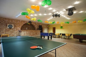Ein Zimmer mit Tischtennisplatte, Dartscheibe und Billardtisch.
