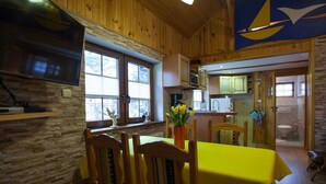 Un intérieur en bois comprenant un coin repas, une cuisine et une salle de bain.