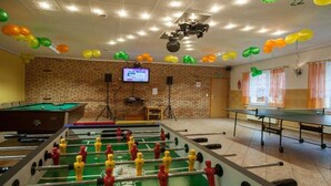 Una stanza con tavolo da calcio, tavolo da biliardo e tavolo da ping pong.