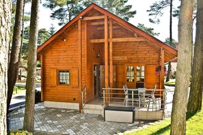 A wooden cabin with a porch, a door, and a window. - Four -anniversary Type B (Dzwirzyno)