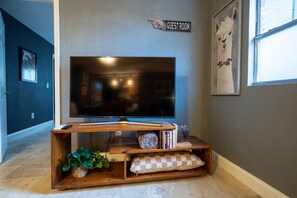 Ein Fernseher auf einem Holzständer mit einem Schild darüber, auf dem 'GUEST ROOM' steht.