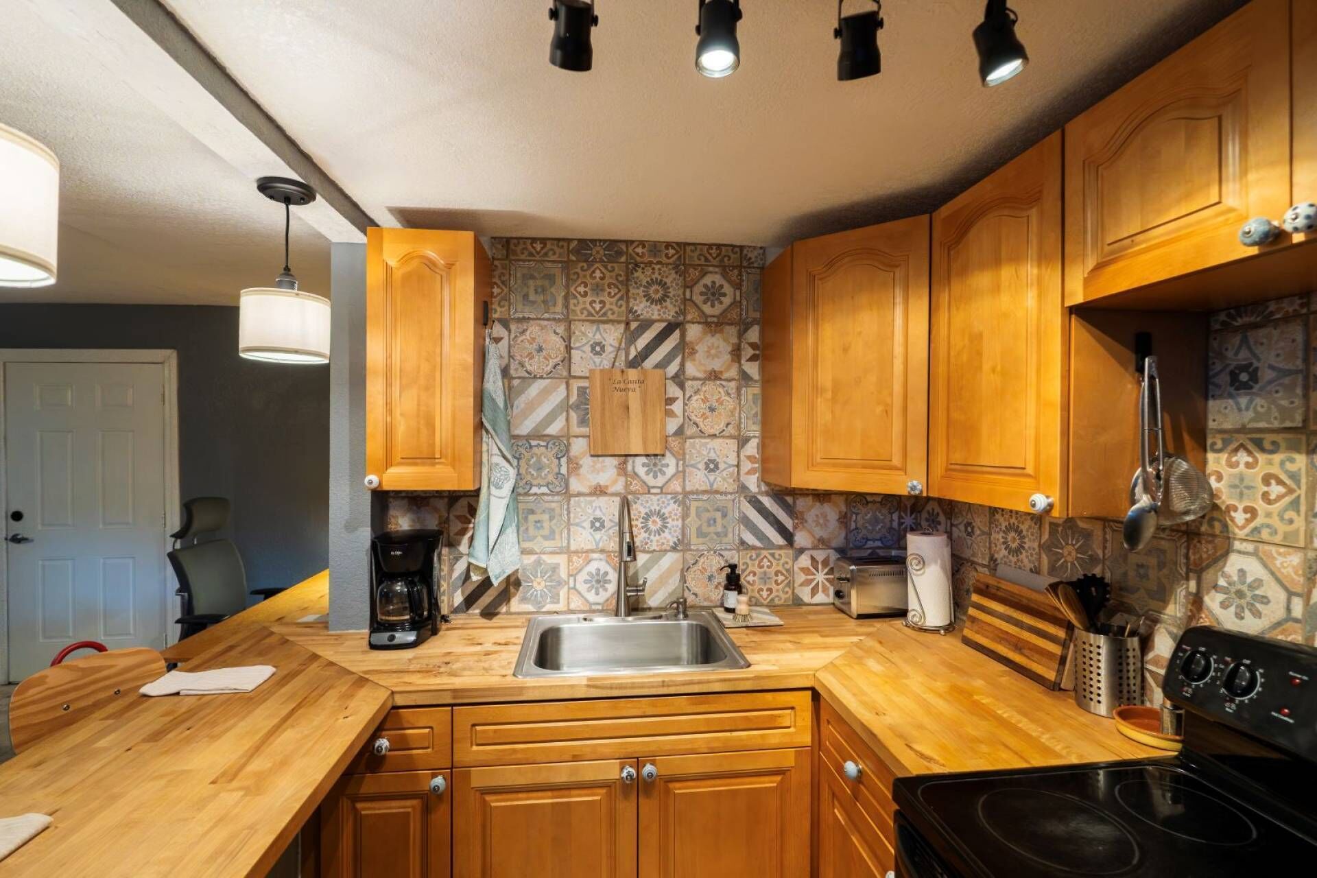 Una cocina con armarios de madera, un lavamanos de acero inoxidable y una estufa negra.