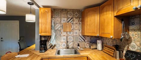 A kitchen with wooden cabinets, a stainless steel sink, and a black stove.