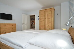 Ein Schlafzimmer mit zwei Betten, einem Fernseher, einem Holzschrank und einer Tür zu einem Badezimmer.