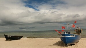 Två båtar på en sandstrand under en molnig himmel.