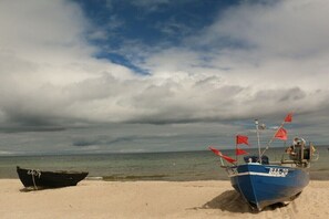 Zwei Boote an einem sandigen Strand unter einem bewölkten Himmel.