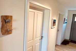 Ein Flur mit Wandverkleidung aus Holz, einer weißen Tür und einem gerahmten Bild an der Wand.