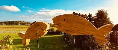 Deux sculptures en bois, représentant des poissons, dans un jardin.