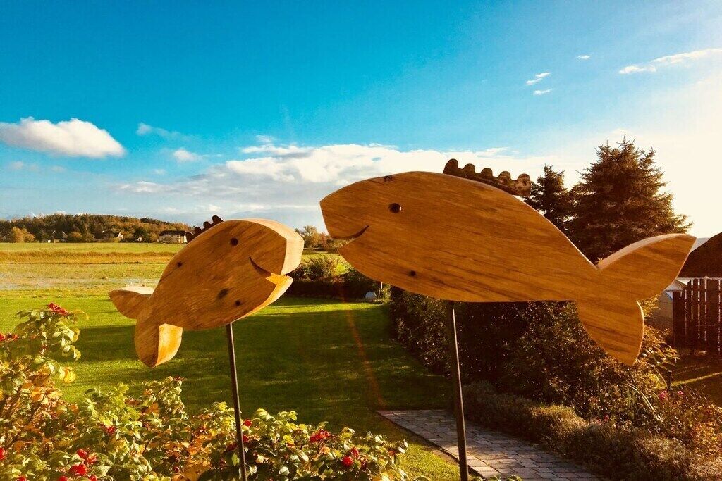 Two wooden fish-shaped sculptures in a garden setting.