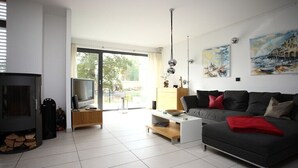 Un salon moderne avec un canapé, un téléviseur, une cheminée et des œuvres d’art accrochées au mur.