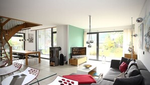 Un salon moderne avec un escalier, un coin repas et de grandes fenêtres.