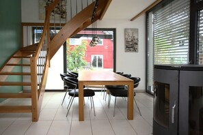 Ein Essbereich mit Holztisch und -stühlen, einer Treppe und Blick auf ein rotes Gebäude.