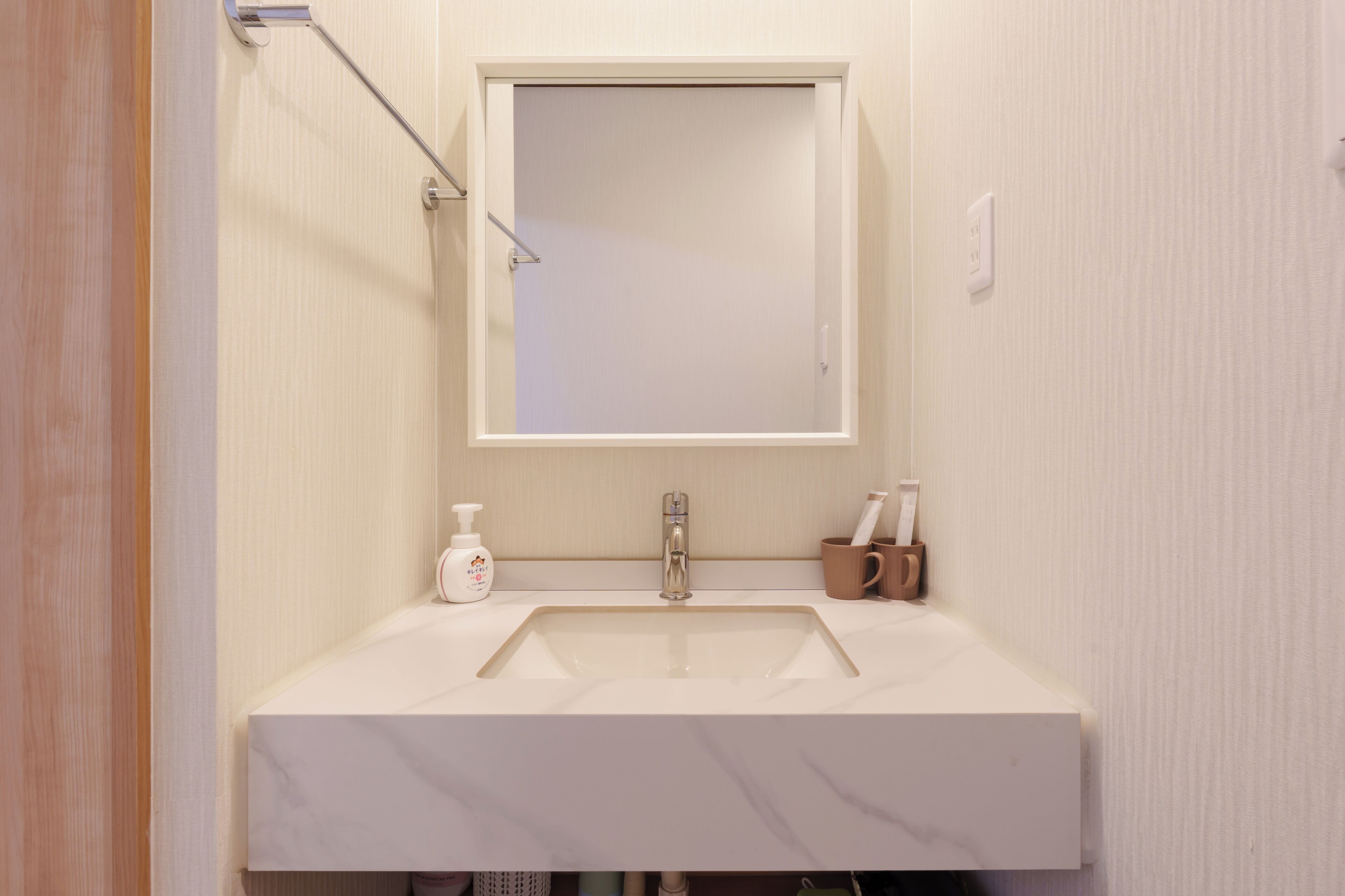 Ein Badezimmer mit Waschbecken, Spiegel, Seifenspender und einer Zahnbürstenhalterung.