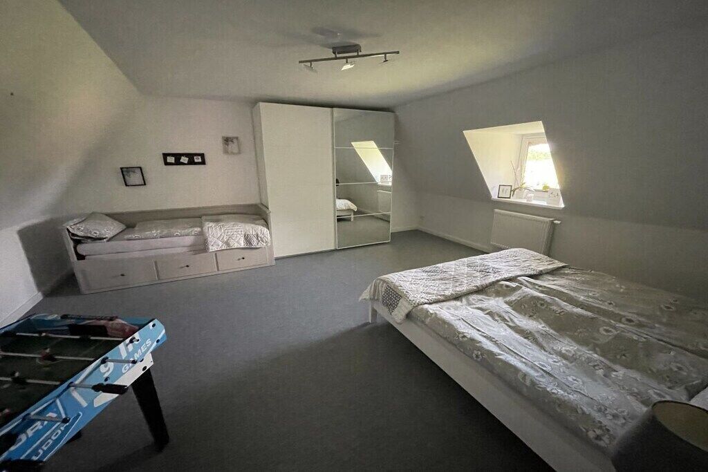 Een slaapkamer met een bed, een kledingkast, een bureau en een raam.