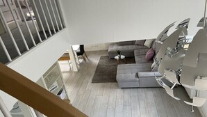Ein modernes Wohnzimmer mit einem grauen Sofa, einem kleinen runden Tisch und einer weißen Heizung.