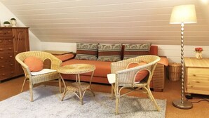 A cozy room with a sofa, two wicker chairs, a small round table, a lamp, and a wooden cabinet. - Holiday home Ockholm (Ockholm)