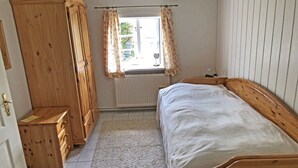 A bedroom with a wooden bed, a wardrobe, and a window with curtains. - Holiday home Ockholm (Ockholm)
