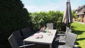 An outdoor dining area with a table and chairs, surrounded by greenery. - Holiday home Ockholm (Ockholm)