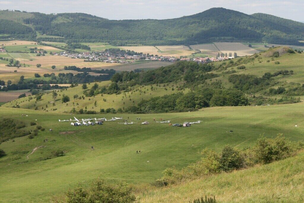 A rural landscape with a small settlement and a field of parked aircraft.