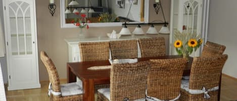 A dining area with wicker chairs, a wooden table, and a vase with sunflowers.