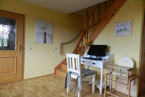 Ein Zimmer mit einer Holztreppe, einem Schreibtisch mit Computer, einem weißen Stuhl und einem kleinen Tisch mit Kinderstuhl.