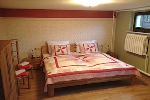 Ein Schlafzimmer mit einem Holzbett, zwei Nachttischen, einem Schrank und einer Heizung.