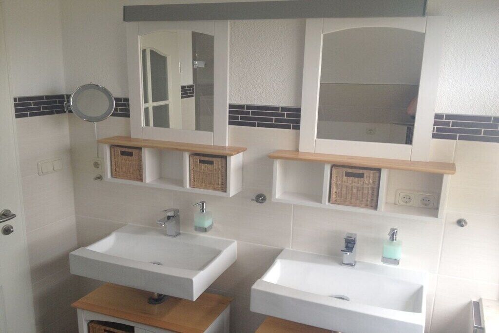 Une salle de bain avec deux lavabos, un miroir et un porte-serviettes.