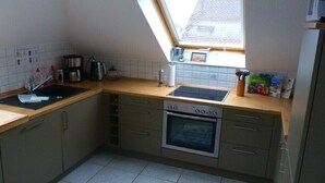 Eine kleine Küche mit Einbauofen, Spüle und einem Fenster über der Arbeitsfläche.