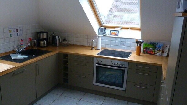 Una cocina compacta con horno integrado, un lavamanos y una ventana sobre la encimera.