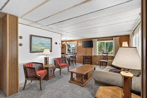 A spacious living room with a wooden ceiling, a dining area with a table and chairs, a sofa, and a television mounted on the wall. - Close to Beach & Dtwn! Extended Long Beach Stay (Long Beach)