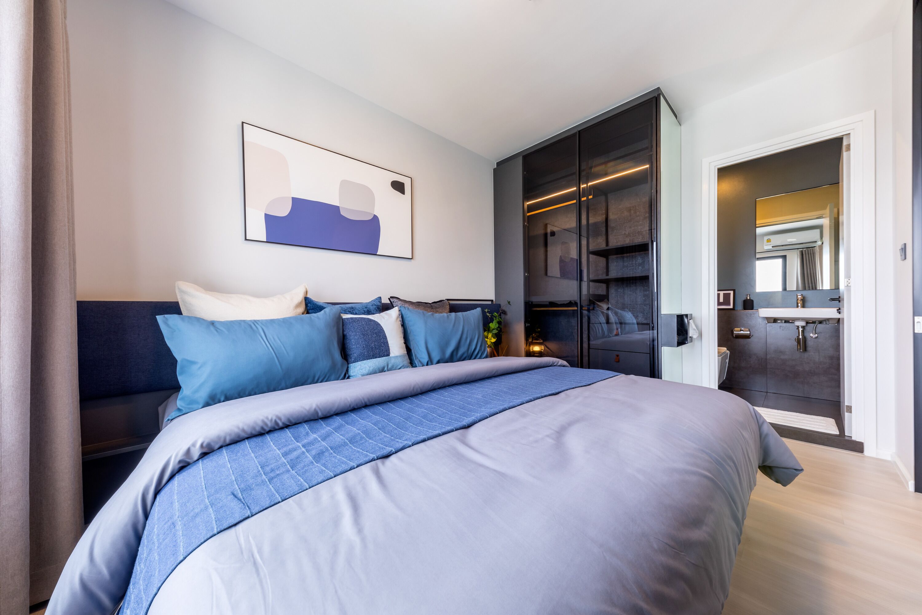 Habitació d'hotel moderna amb un llit gran, un armari, un bany i un quadre a la paret.
