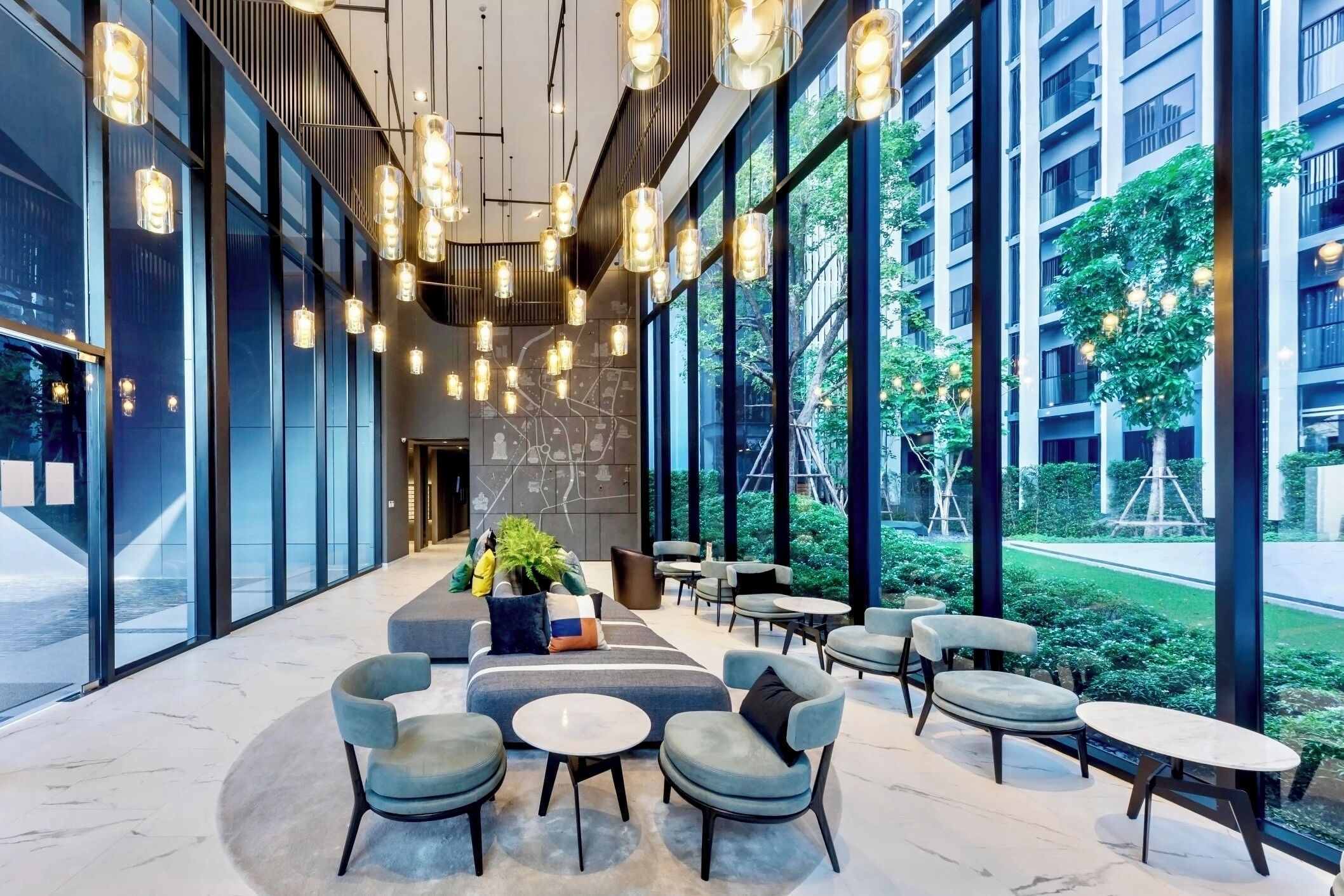 A modern indoor seating area with round tables and chairs, large windows, and hanging pendant lights.