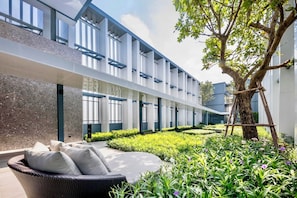 A modern building with a covered outdoor seating area and a garden. - Top-Floor Condo Next to MRT Blue Line, Near Malls, Pool, Gym & Quiet Living (Krung Thep Maha Nakhon)