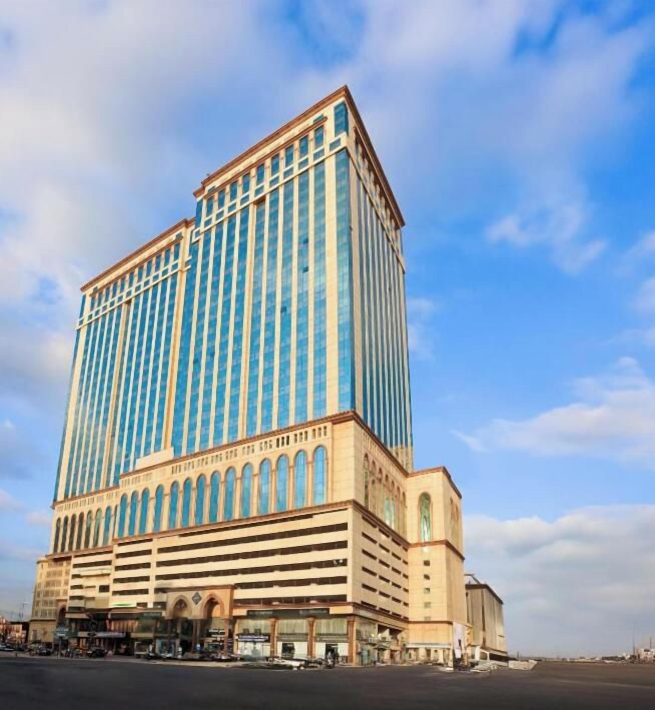 Un hotel moderno de gran altura, con una estructura vertical destacada y una sección inferior con una serie de arcos.