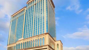 A high-rise hotel with a modern design, featuring a prominent vertical structure and a lower section with a series of arches.