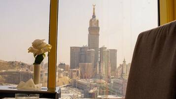 A room with a view of a cityscape, a vase with a single flower, and a table with a tissue box.
