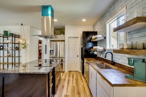 A modern kitchen with a central island, stainless steel appliances, and a black backsplash. - Historic Southside Fort Worth Home w/ Fenced Yard! (Fort Worth)