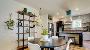 A modern kitchen with a central island, white chairs, and a wooden floor. - Historic Southside Fort Worth Home w/ Fenced Yard! (Fort Worth)