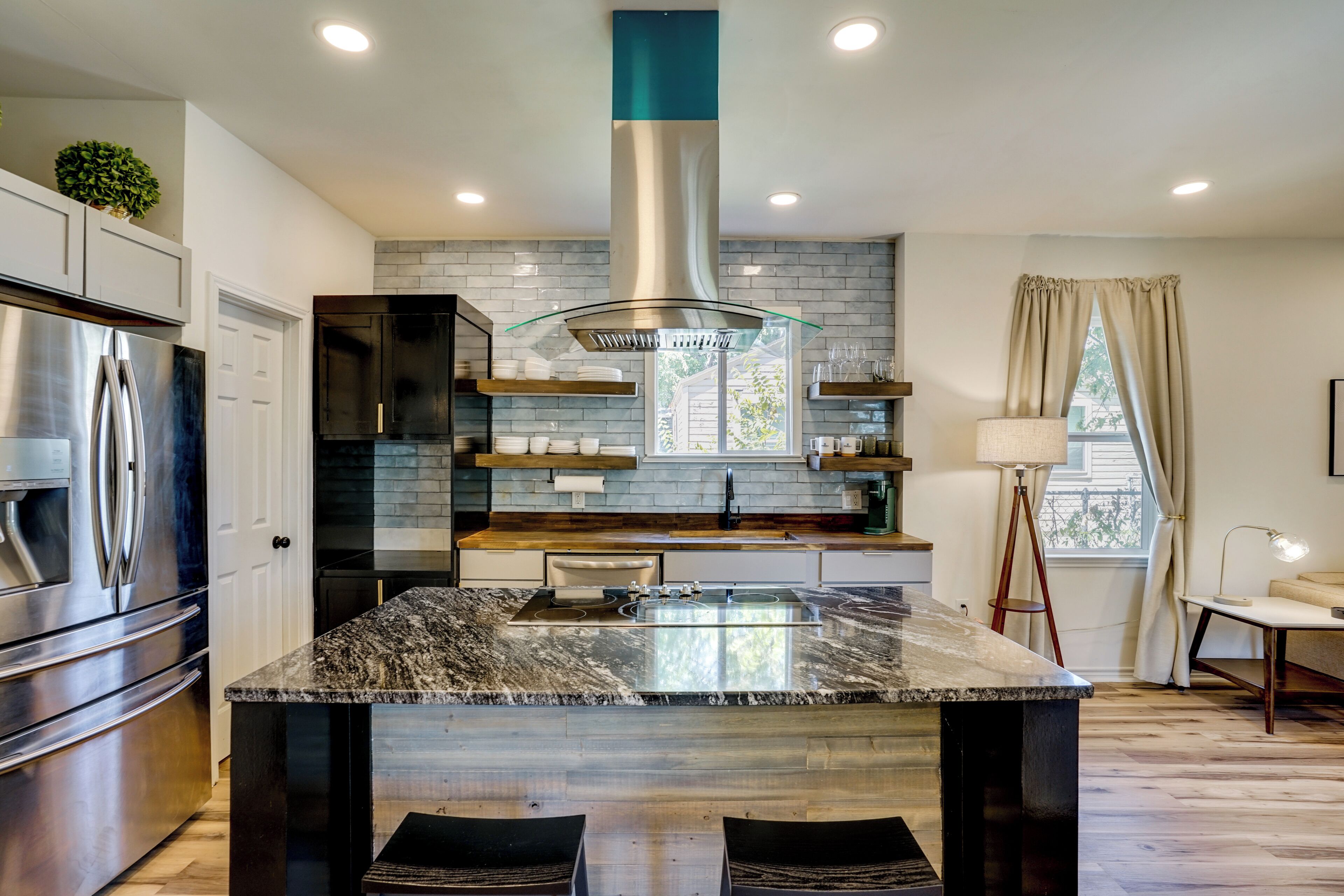A modern kitchen with a central island, stainless steel appliances, and a view to the outdoors.
