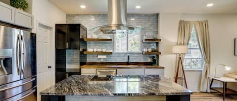 A modern kitchen with a central island, stainless steel appliances, and a view to the outdoors.
