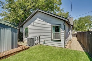 Une maison de plain-pied avec un toit à pignon, un petit jardin devant et une clôture en bois.