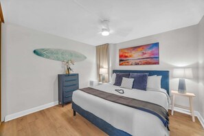 A bedroom with a bed, a dresser, a painting, and a ceiling fan. - Diredt Oceanfront 1BR with amazing views, pool, hot tub, lani and AC-Maalaea Banyans 310 (Wailuku)