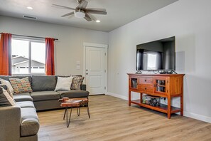 Un salon comprenant un canapé, une table basse, un meuble en bois, un téléviseur et un ventilateur de plafond.