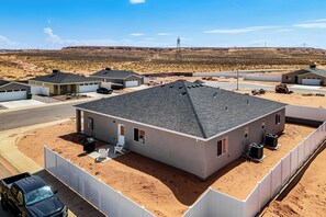 A residential area with houses, a paved driveway, and a clear sky. - Explore Glen Canyon/Lake Powell! Red River Retreat (Page)