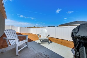 A patio with two white chairs, a barbecue grill, and a white fence. - Explore Glen Canyon/Lake Powell! Red River Retreat (Page)