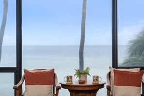 Een kamer met twee houten stoelen gericht op een raam met uitzicht op zee.