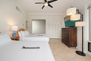 A hotel room with two beds, a ceiling fan, a large mirror, a wardrobe, and a floor lamp. - 2BR, 3BA Oceanfront retreat with pool, balcony, and beach access-Kapalua Bay Villas 23B3 (Lahaina)