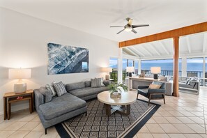 A modern living room with a sectional sofa, a round coffee table, and a view of the ocean. - 2BR, 3BA Oceanfront retreat with pool, balcony, and beach access-Kapalua Bay Villas 23B3 (Lahaina)