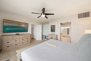 A bedroom with a bed, a dresser, a television, and a ceiling fan. - 2BR, 3BA Oceanfront retreat with pool, balcony, and beach access-Kapalua Bay Villas 23B3 (Lahaina)
